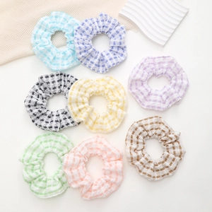 Lot de huit chouchous à carreaux colorés aux tons pastels doux sur un fond blanc épuré