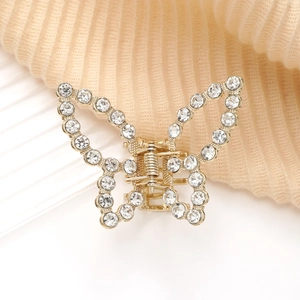Détail de la pince à cheveux papillon dorée ornée de strass brillants et élégants