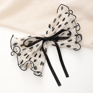 Detail of white pleated bow hair clip with black polka dots and fine wavy edges