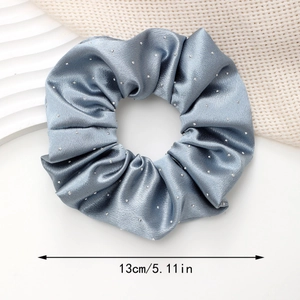 Detail view of a 13cm grey blue satin scrunchie with rhinestones on white wavy props