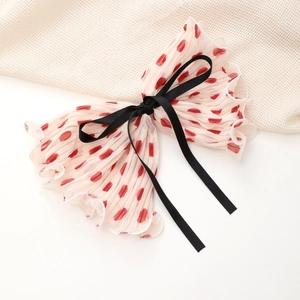 Close-up of pleated chiffon bow with red polka dots and black ribbon streamers