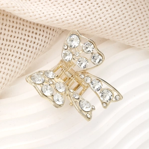 Détail de la pince à cheveux papillon dorée ornée de strass brillants et de métal poli