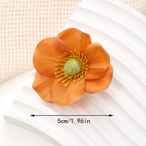 Close-up of 5cm orange fabric flower hair clip with yellow stamen and soft texture detail
