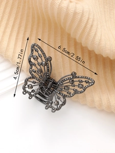 Détail d'une pince à cheveux papillon en métal avec strass gris, mesurant 6,5 cm de long