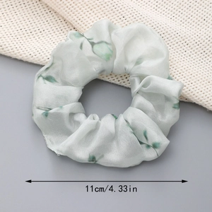 Vue détaillée du chouchou floral en organza de 11 cm avec des motifs de feuilles vertes