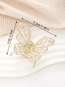 Détail d'une pince à cheveux papillon dorée de 6,5 cm ornée de perles élégantes
