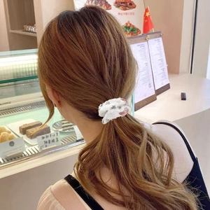 Close-up of a white butterfly hair scrunchie with red floral patterns for low ponytail styling