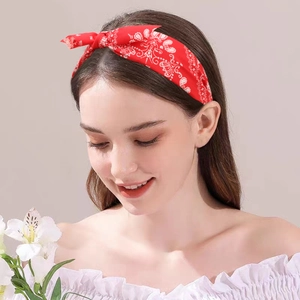 Red paisley print headband with cute bow detail worn by a model on a clean background