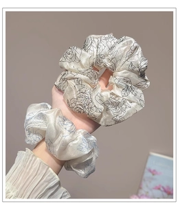 Close-up of vintage floral satin scrunchies in black and light blue on a hand