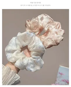 Close-up of oversized floral silk scrunchies in ivory and champagne with rose patterns