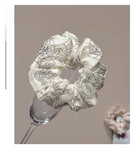 Detail of elegant cream floral scrunchie with black rose print on a glass rim