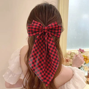 Elegant red and black plaid bow hair clip with long ribbons worn on a ponytail