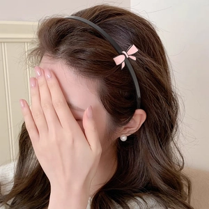 Serre-tête noir élégant avec petit nœud en soie rose sur fond beige clair minimaliste