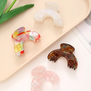 Set of four acetic acid hair claws with tortoise and pearl textures on a beige tray