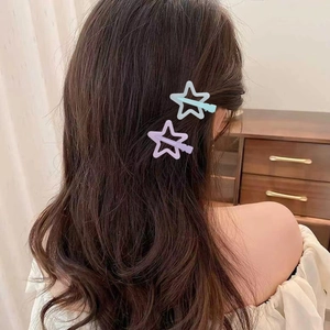 Close-up of mint green and lavender star-shaped hair clips worn on a girl's hair