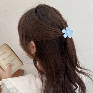 Dettaglio della clip per capelli a fiore azzurro opaco indossata su un raccolto