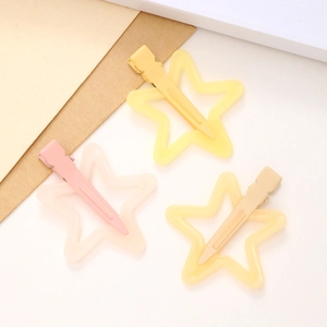 Detail of star-shaped hair clips in yellow, pink, and cream with a matte resin finish
