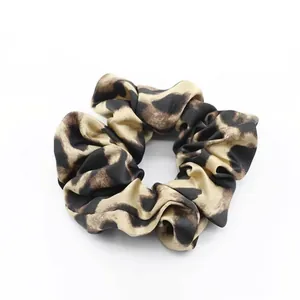 Detailed texture of leopard print satin scrunchie with soft pleated silk-like fabric