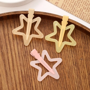Three jelly star-shaped hair clips in cream, yellow, and pink colors on wooden tray