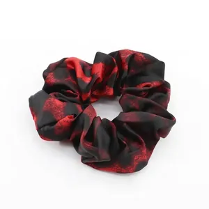 Detailed view of large leopard scrunchie with red marble pattern and satin finish
