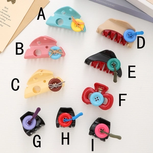 Detail view of colorful cheese-shaped and button-decorated hair claw clips in various styles