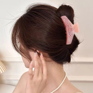 Pince à cheveux rose en acétate avec motif de fleurs en cristal sur une coiffure en chignon