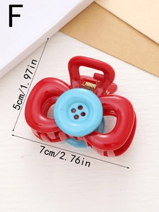 Detail view of a red hair claw clip with a blue button decoration and size measurements