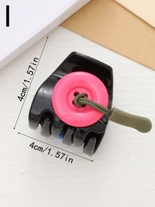Detail view of 4cm black hair claw clip with pink button and green drawstring accents