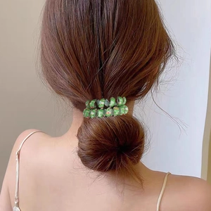 Élastique cheveux spirale vert aux motifs de Noël porté sur un chignon de femme