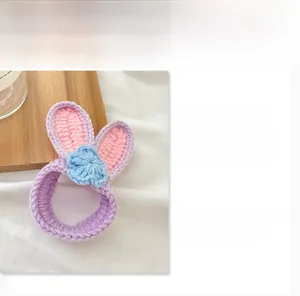 Dettaglio dell'elastico per capelli all'uncinetto con orecchie di coniglio e fiore blu