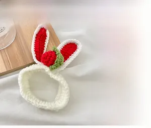 Dettaglio dell'elastico per capelli bianco all'uncinetto con orecchie di coniglio e fragola