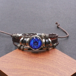 Detail van vintage gevlochten leren armband met blauwe Leeuw sterrenbeeld op houten vlak