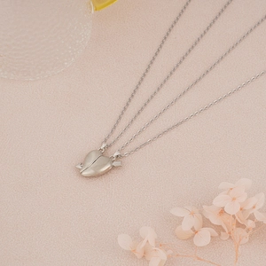 Detail of magnetic silver heart pendants for couples on a warm decorative background