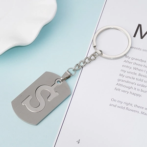 Minimalist silver stainless steel keychain with hollowed S-letter tag on blue backdrop