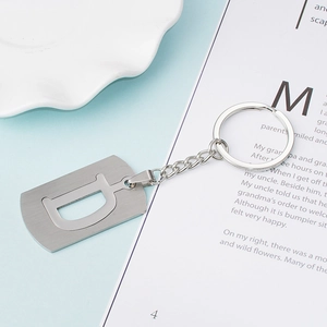 Brushed stainless steel key ring with letter D charm on a minimalist blue background