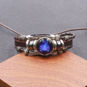 Detail van gevlochten leren Schorpioen-armband met lichtgevende glazen bedel