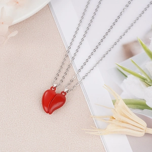 Detail shot of magnetic red heart couple necklace pendants on a white textured surface