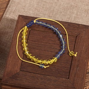 Vue détaillée des perles de cristal jaune et bleu sur un bracelet tressé ajustable