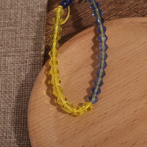 Bracelet de perles en cristal bleu et jaune drapeau Ukraine sur plateau bois et lin