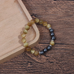 Detail of 8mm tiger eye beads and grey hematite stones on a wooden tray