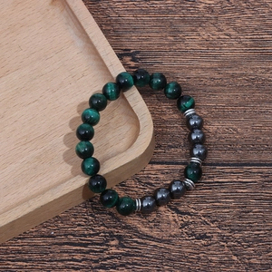 Detailed close-up of 8mm green tiger eye and hematite beaded bracelet on a wood tray