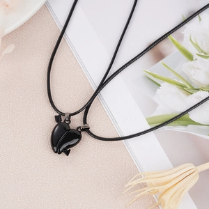 Detail of couple magnetic heart necklaces with Cupid's arrow design and black cord