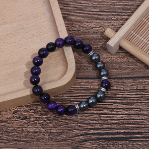 Detailed macro of 8mm purple tiger eye and hematite beaded bracelet on wooden tray