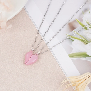Detail of pink magnetic heart necklaces for couples on elegant floral background
