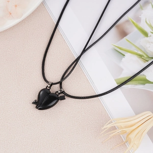 Detail of magnetic interlocking heart pendants on black woven ropes for couples