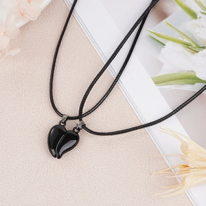 Detailed view of black magnetic heart pendants with woven ropes for couples necklaces