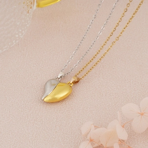 Close-up of magnetic heart pendants in gold and silver finish for couples jewelry
