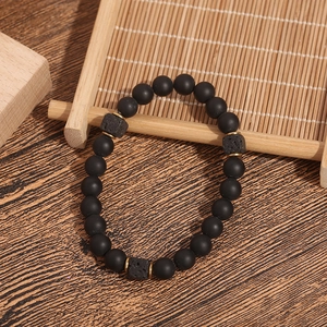 Detail of lava rock square beads and matte black onyx beads on a natural wooden background