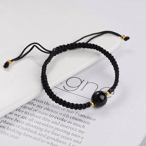 Detail eines handgewebten schwarzen Armbands mit Obsidianperle und Goldakzenten