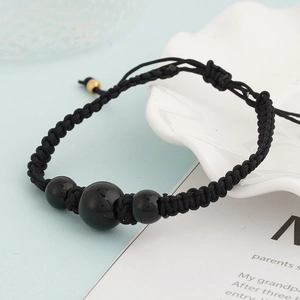 Detailaufnahme des schwarzen Obsidian-Armbands aus gewebter Kordel mit Goldperlen-Verschluss